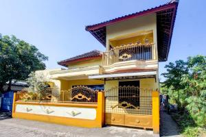 een geel huis met twee honden in kooien bij OYO Life 92846 Kost Putra Griya Eka in Tanjungkarang
