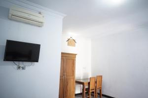 um quarto com uma televisão e uma mesa com cadeiras em OYO Life 92886 Rumah Nyaman Radhika 2 Syariah em Tuban