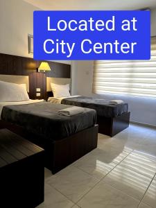 two beds in a hotel room with the words located at city center at Petra Town Check-Inn in Wadi Musa