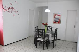 un comedor con una mesa con sillas y un jarrón de flores en Apartamento Mobiliado AptCE, en Fortaleza