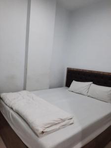 uma cama com lençóis brancos e almofadas em OYO Life 92883 Kost Ratana Cengkareng Syariah em Jakarta