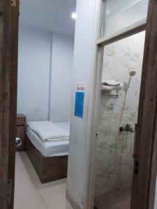 um pequeno quarto com uma pequena cama e um chuveiro em OYO Life 92883 Kost Ratana Cengkareng Syariah em Jakarta