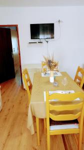 uma mesa de jantar amarela com cadeiras e uma televisão em Apartman Barbara em Fužine