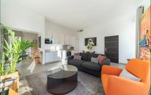 uma sala de estar com um sofá preto e cadeiras laranja em AMAZING & MODERN 2-Bedrooms em Cannes