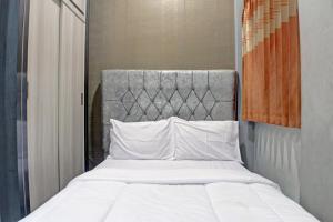 - un lit avec des draps et des oreillers blancs dans l'établissement OYO Life 92830 Homestay Slamet Riadi Iv, à Bandar Lampung