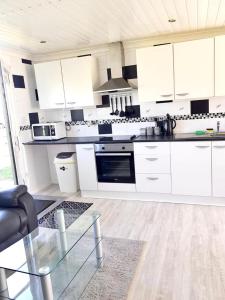 a kitchen with white cabinets and a glass table at Summer Days in Camber