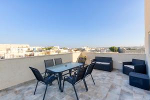 uma mesa e cadeiras numa varanda com vista em Annitchka Mansions - Penthouse in central Malta em Birkirkara