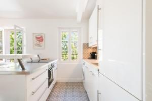 una cocina blanca con armarios blancos y fregadero en RIVIERA en Saint-Tropez