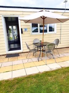 a table and chairs with an umbrella on a patio at Summer Days in Camber