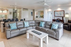 a living room with a couch and a table at POINCIANA 101 HAMILTON ISLAND CENTRALLY LOCATED 3 BEDROOM, plus BUGGY!! in Hamilton Island