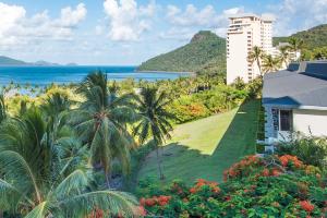 a view of a resort with palm trees and the ocean at POINCIANA 101 HAMILTON ISLAND CENTRALLY LOCATED 3 BEDROOM, plus BUGGY!! in Hamilton Island