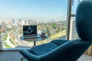 a blue chair with a laptop on a table in front of a window at DoubleTree by Hilton Santiago Kennedy, Chile in Santiago