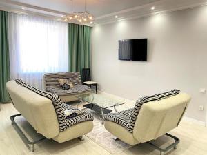 a living room with two chairs and a tv at Luxe Apartments on Stepnoy in Karagandy