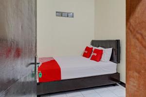 Un dormitorio con una cama con almohadas rojas. en OYO Life 92685 Kost Arimbi, en Bandung