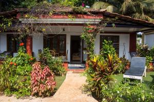 una casa con plantas y una silla delante de ella en Shikara Beach Resort, en Cavelossim