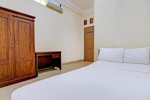a bedroom with a bed and a wooden cabinet at OYO Life 92663 Karmel 6 in Purwokerto