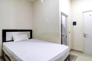 a bedroom with a bed with white sheets and a window at OYO Life 92707 D-akomiba Residence in Jambi