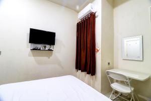 a bedroom with a bed and a desk and a tv at OYO Life 92707 D-akomiba Residence in Jambi