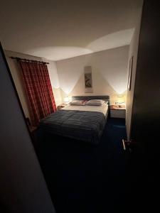 - une petite chambre avec un lit et un rideau rouge dans l'établissement [Dolomiti] Paradiso in montagna nel verde + Sauna, à Carisolo