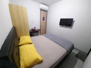 een slaapkamer met een bed met gele kussens en een televisie bij OYO Life 92770 Cozy Puri 22 in Jakarta