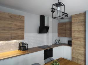 a kitchen with white and wooden cabinets and a black chandelier at Apartament Homole E1 z ogródkiem in Szczawnica