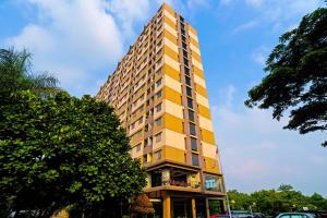 a tall yellow building with cars parked in front of it at OYO Life 92774 The Edge Apartment By My Home in Cimahi