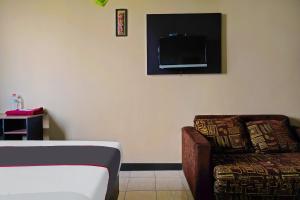 a room with a bed and a chair and a tv at OYO Life 92774 The Edge Apartment By My Home in Cimahi