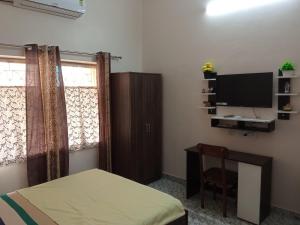 a bedroom with a bed and a tv and a chair at Dey Niwas in Dum Dum