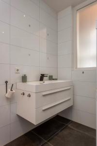 uma casa de banho branca com um lavatório e uma janela em Kerkakker0 Luxery apartment with garden in the city center em Eindhoven