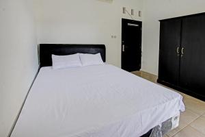OYO Life 92754 Kost Griya Perdana في ماتارام: سرير أبيض مع اللوح الأمامي الأسود في غرفة النوم