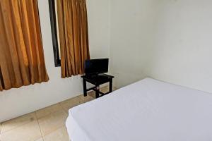 OYO Life 92754 Kost Griya Perdana في ماتارام: غرفة نوم بسرير وتلفزيون على طاولة