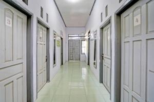 pasillo con puertas blancas y suelo de baldosa blanca en OYO Life 92937 Kost Putri Sarkara Syariah, en Banyuwangi