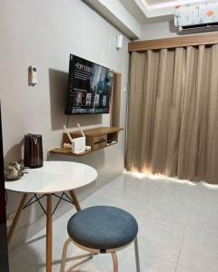 a room with a table and a tv and a chair at Paragon Village Apartment by CityDoorz in Galuga +11 photos