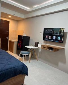 a bedroom with a bed and a flat screen tv at Paragon Village Apartment by CityDoorz in Galuga