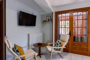 a living room with two chairs and a table and a television at Casa Feli - APARTAMENTO con JARDÍN PRIVADO en los PIRINEOS in Castiello de Jaca