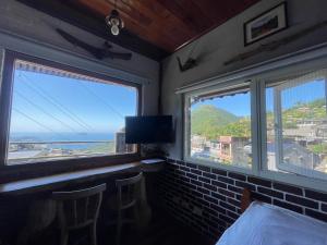 a room with two windows with a view of the ocean at 九份山海灣民宿 I 近老街 l 海景檜木房 in Jiufen