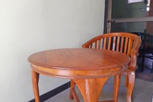 a wooden table and chair sitting next to a wall at OYO Life 92915 Duta Amnan Syariah in Sidoarjo