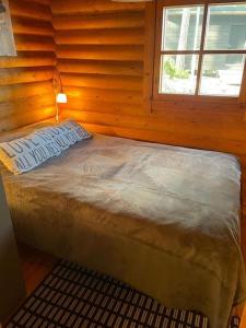 een bed in een houten kamer met een raam bij Rantahuvila Naantalissa in Naantali