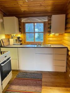 a kitchen with white cabinets and a sink and a window at Rantahuvila Naantalissa in Naantali