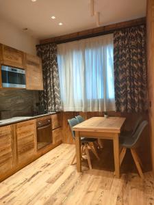 cocina con mesa de madera, sillas y ventana en Fior di Roccia Apartments en Breuil-Cervinia