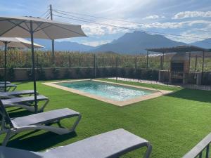 une cour avec une piscine, 2 chaises et un parasol dans l'établissement Ca la Joia Casa con piscina privada en la Vall d'en Bas, à Les Preses
