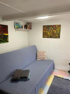 un divano blu in una stanza con dipinti sul muro di Stāsti a Upesgrīva