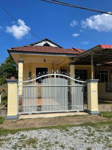 uma pequena casa amarela com um portão branco em AR HOMESTAY KUALA TERENGGANU em Kuala Terengganu