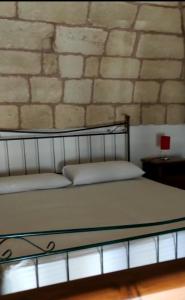 een bed in een kamer met een stenen muur bij Rosina in Cannole