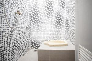 a white tiled bathroom with a toilet in a shower at OYO Life 93017 Kost H Soeroso in Situbondo