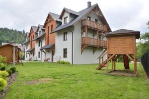 a group of houses with a playground in a yard at Apartament Homole E1 z ogródkiem in Szczawnica
