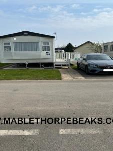 a car parked on the side of a road next to a house at 3 Bed 2 Bath Static Mobile Home On Fantastic Park in Mablethorpe