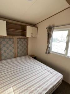 a small bedroom with a bed and a window at 3 Bed 2 Bath Static Mobile Home On Fantastic Park in Mablethorpe