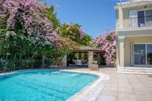 a house with a swimming pool and flowering trees at Villa Grosse Sea and Mountains View in Gastourion