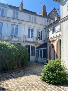 una gran casa blanca con una calle adoquinada delante de ella en La maison familiale en Auxerre